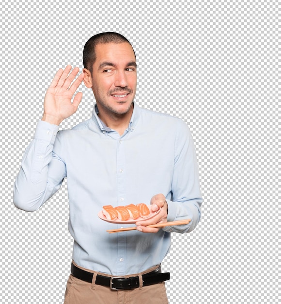 Young man using chopsticks to eat sushi