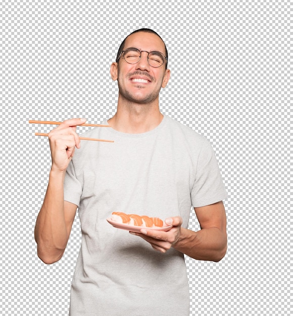 Young man using chopsticks to eat sushi