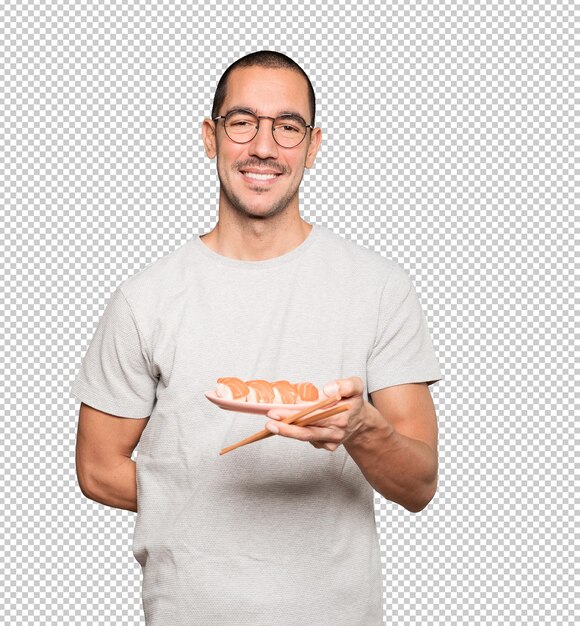 Young man using chopsticks to eat sushi