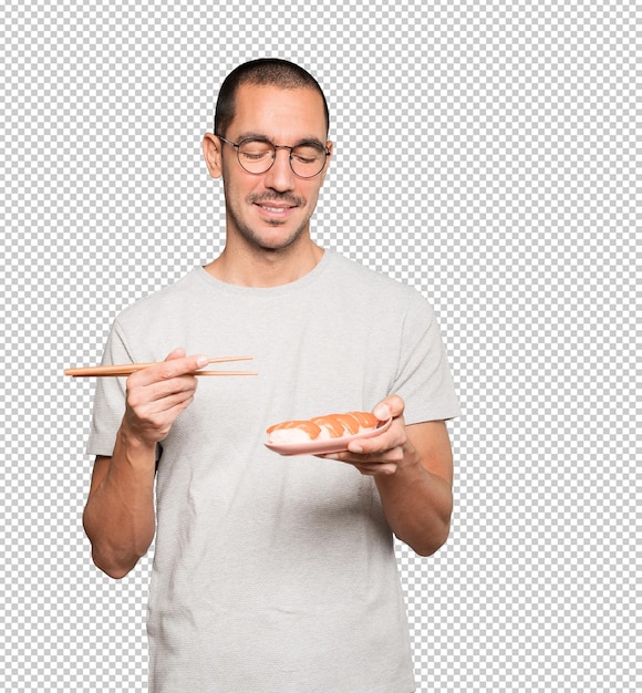 Young man using chopsticks to eat sushi