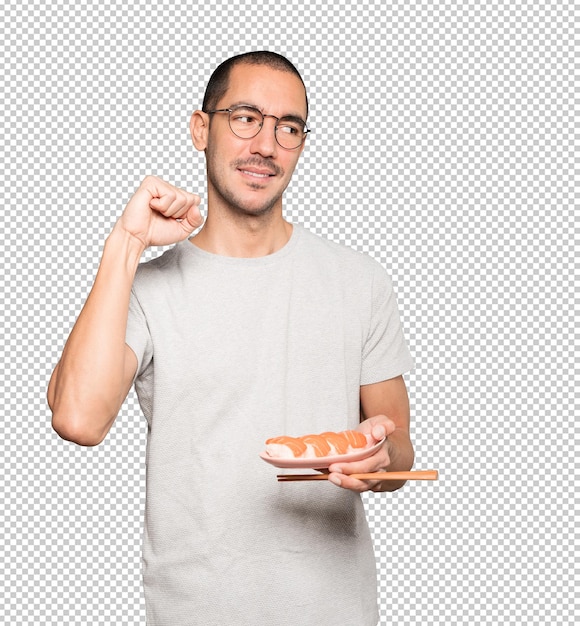 Young man using chopsticks to eat sushi