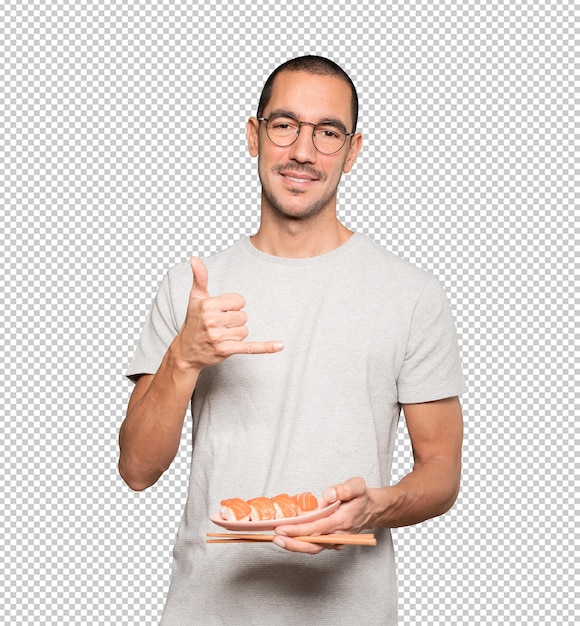 Young man using chopsticks to eat sushi