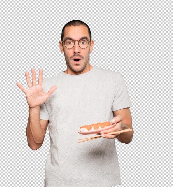 Young man using chopsticks to eat sushi