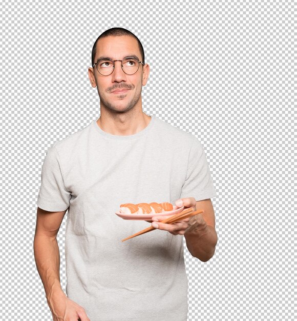 Young man using chopsticks to eat sushi