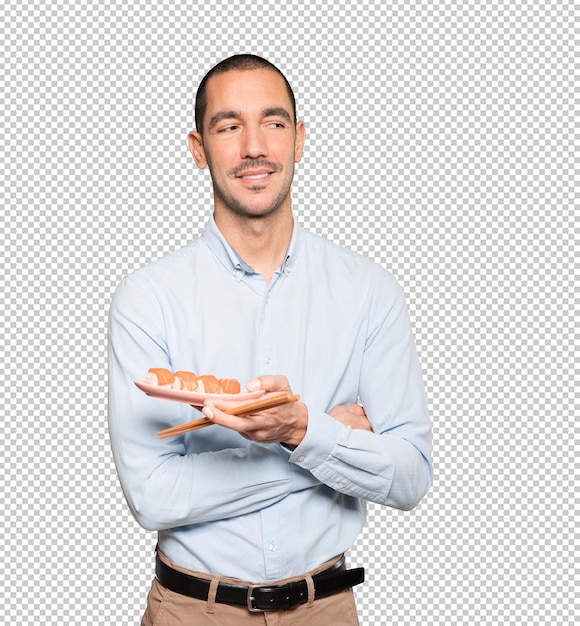 Young man using chopsticks to eat sushi