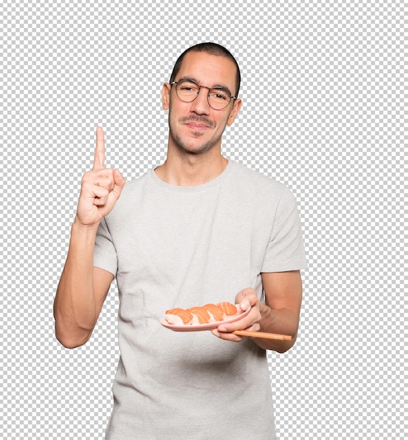 Young man using chopsticks to eat sushi