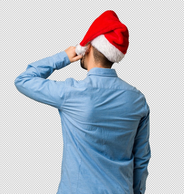 PSD young man wearing santa hat from behind thinking about something