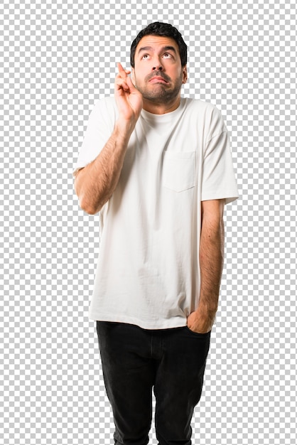 Young man with white shirt with fingers crossing and wishing the best. Making a wish.