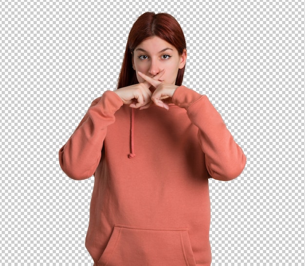 Young redhead girl with pink sweatshirt showing a sign of closing mouth and silence gesture