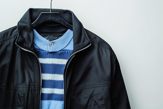 Vector a black jacket with a blue stripe and a striped shirt hanging on a hanger