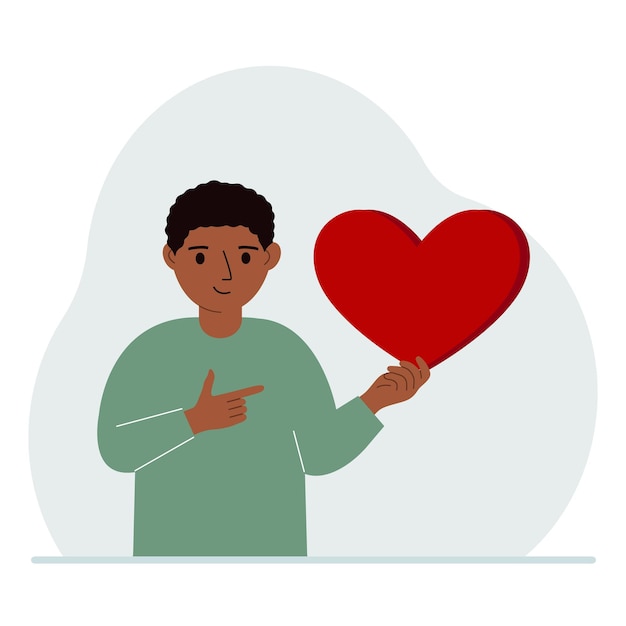 A boy holds a big red heart in his hand The concept of volunteering romantic relationship or love