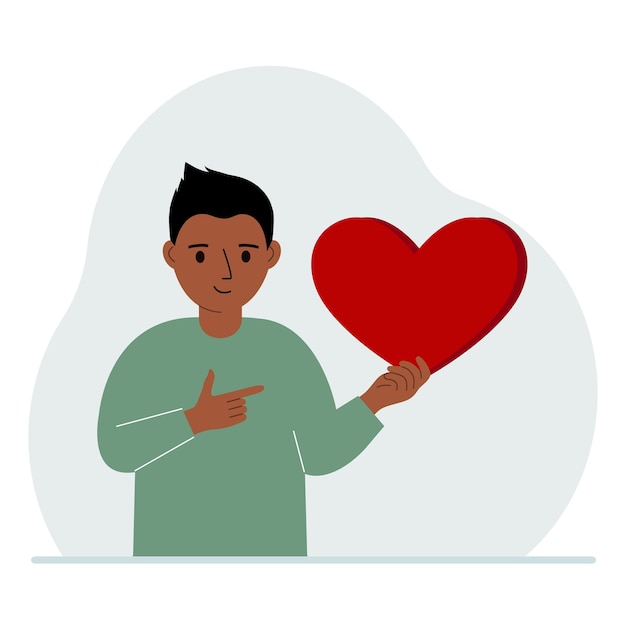 A boy holds a big red heart in his hand The concept of volunteering romantic relationship or love