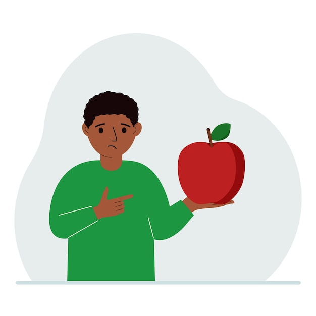 A boy holds a fresh and red apple in his hand Boy eats an apple Healthy food concept