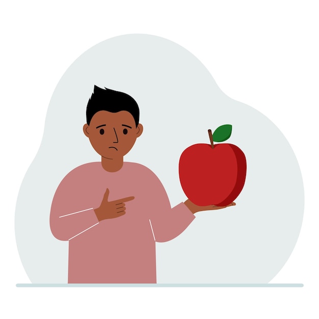 A boy holds a fresh and red apple in his hand Boy eats an apple Healthy food concept