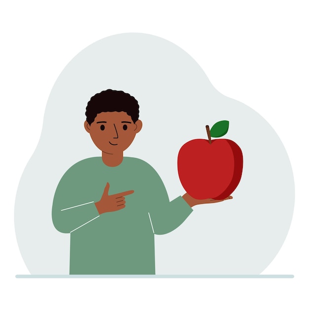 A boy holds a fresh and red apple in his hand Boy eats an apple Healthy food concept