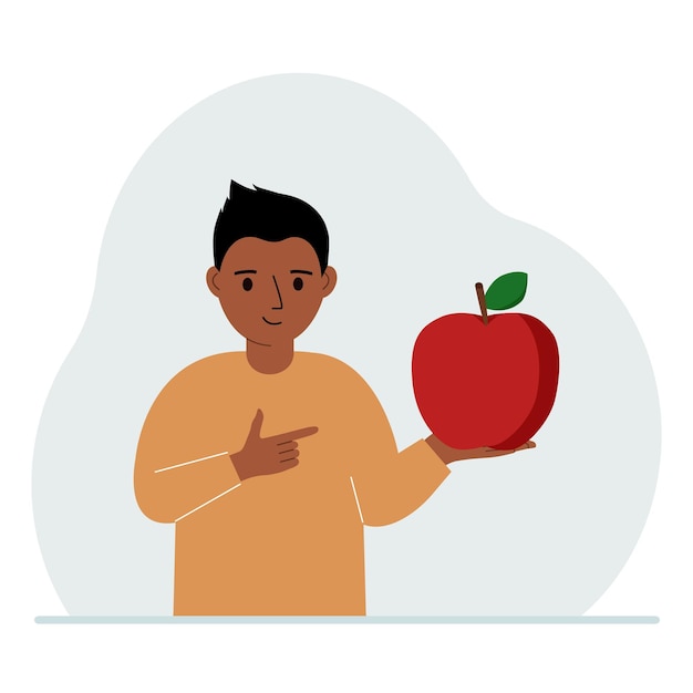 A boy holds a fresh and red apple in his hand Boy eats an apple Healthy food concept