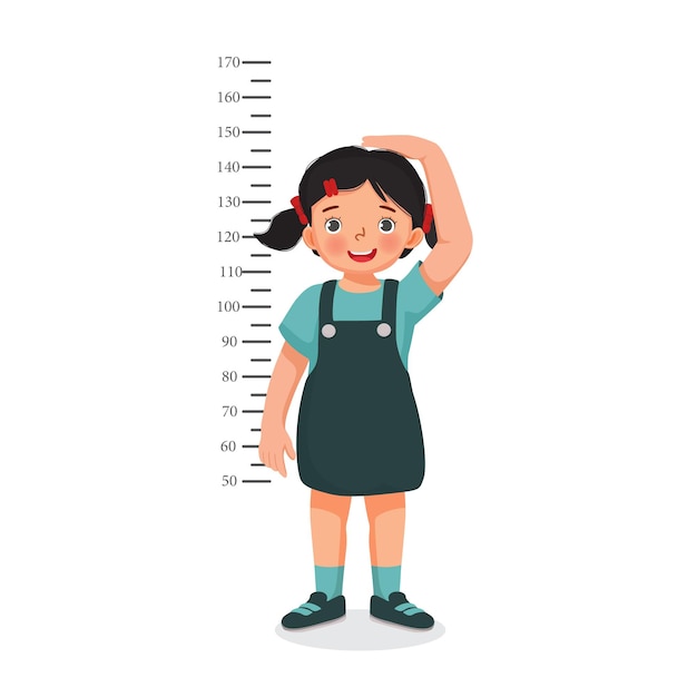 Cute Little girl measuring height of her growth on the background of wall