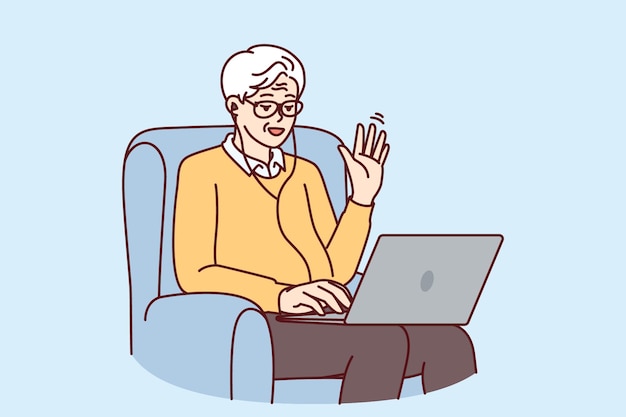 Elderly man makes video call through laptop sitting in chair and waving hand greeting interlocutor