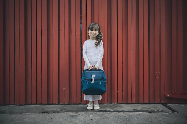 a girl with a blue bag stands in front of a red wall