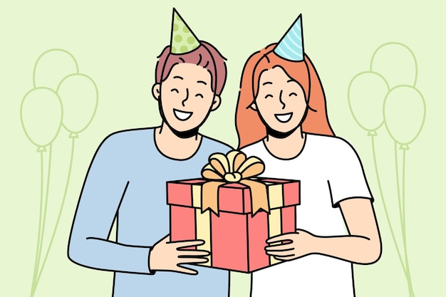 Guy girl in party hats are smiling holding box