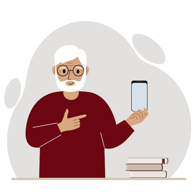 A happy grandfather holds a mobile phone in one hand and points at it with the index finger of his other hand.