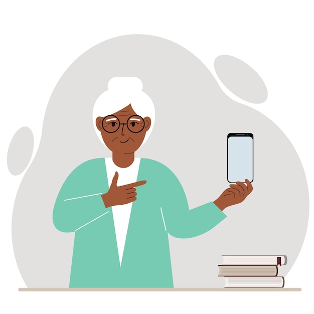 A happy grandmother holds a mobile phone in one hand and points at it with the index finger of his other hand.