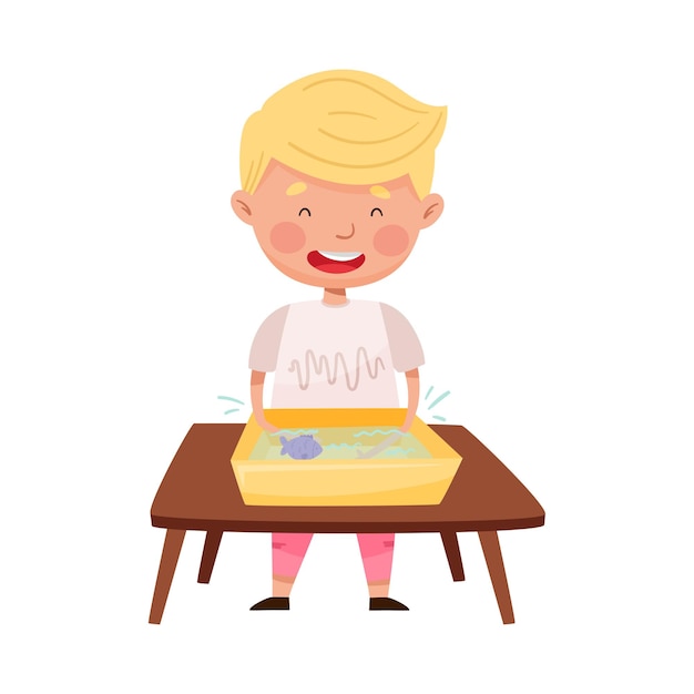 Vector little boy standing at table and splashing in water basin with fish vector illustration