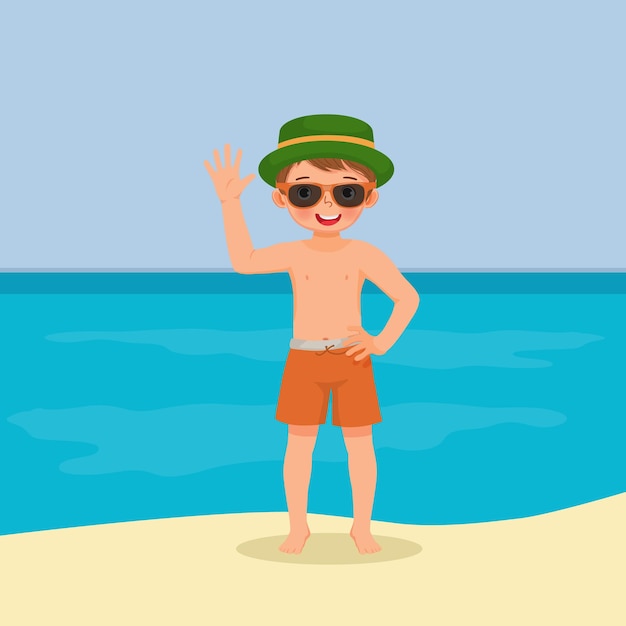 little boy in swimsuit with hat and sunglasses having fun on beach waving hand posing on summertime