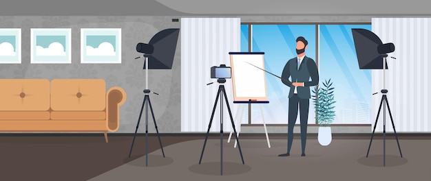 A man in a business suit with a tie is giving a presentation to the camera. The teacher is writing a lesson. The concept of blogging, online training and conferences. Camera on a tripod, softbox.