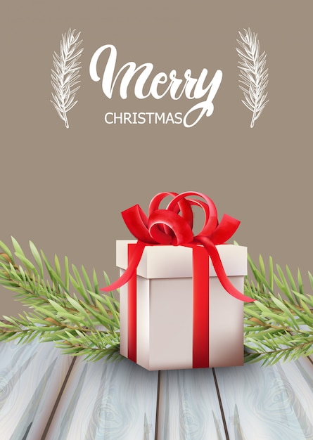 Merry christmas gift box with red ribbon and fir tree leaves