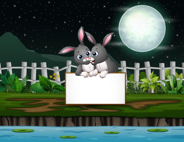 Night landscape with bunnies cartoon holding blank sign by the lake