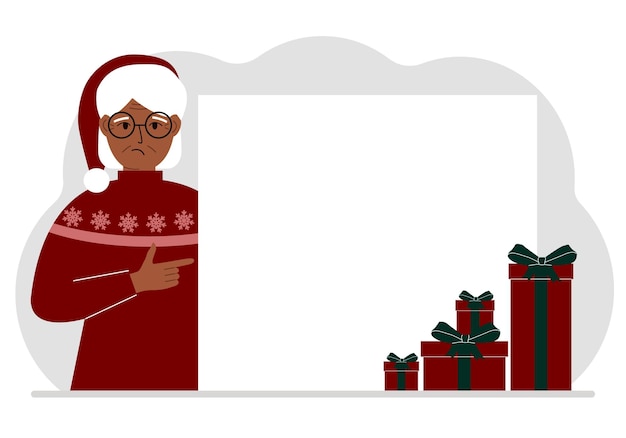 A old woman in a Christmas or New Year's sweater with a red sana cap points his finger at a banner a blank poster or a large white sheet of paper with space for text