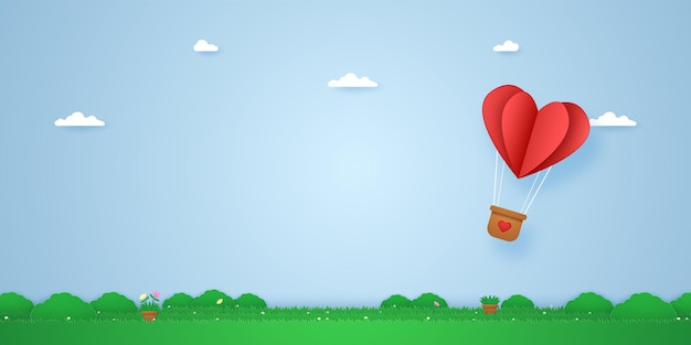 Red folded heart hot air balloon flying over grass i paper art style