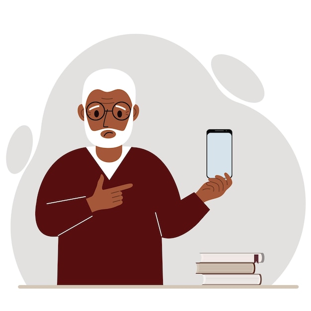 A sad grandfather holds a mobile phone in one hand and points at it with the index finger of his other hand.