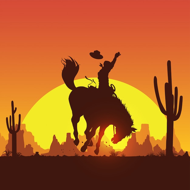 Silhouette of a cowboy riding a wild horse at sunset