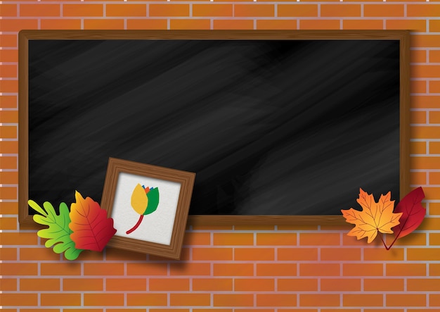 Small wooden photo frame with autumn leaves on school blackboard and brick wall background