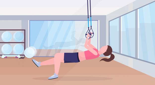 Vector sporty woman doing exercises with suspension fitness straps elastic rope girl training crossfit workout concept modern gym studio interior horizontal flat full length