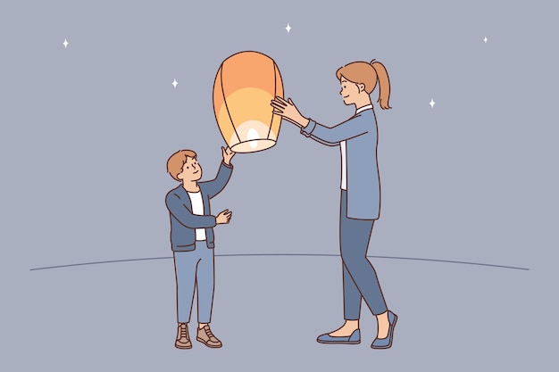 Teenage boy together with older sister launch air fire lantern standing on street under starry sky