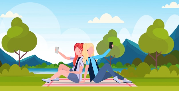 two women taking selfie photo on smartphone camera female cartoon characters sitting back to back each other and posing outdoor nature landscape background  full length horizontal