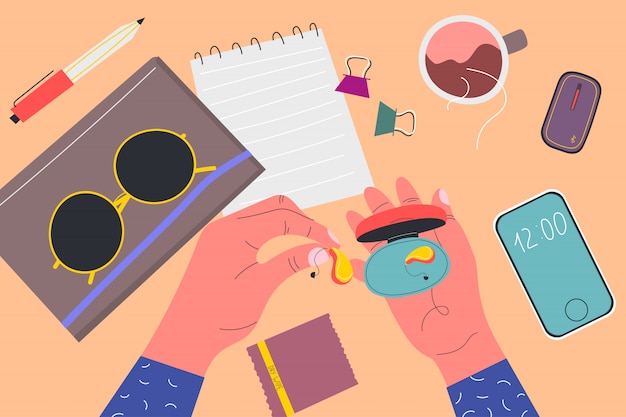 View from above. Men's holds box from under the hearing aid. Notebooks, sunglasses, phone, wipe, pen, clamps, cup of tea, device. Colorful  illustration in flat cartoon style.