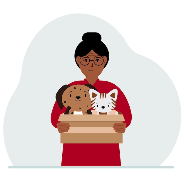 A woman holds a cardboard box with a cat and a dog The concept of rescue help and care for pets