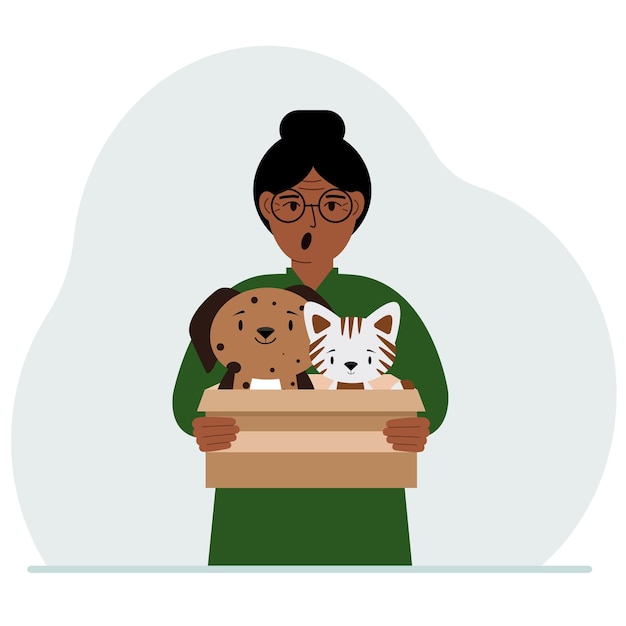 A woman holds a cardboard box with a cat and a dog The concept of rescue help and care for pets