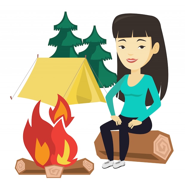 Woman sitting on log near campfire in the camping.