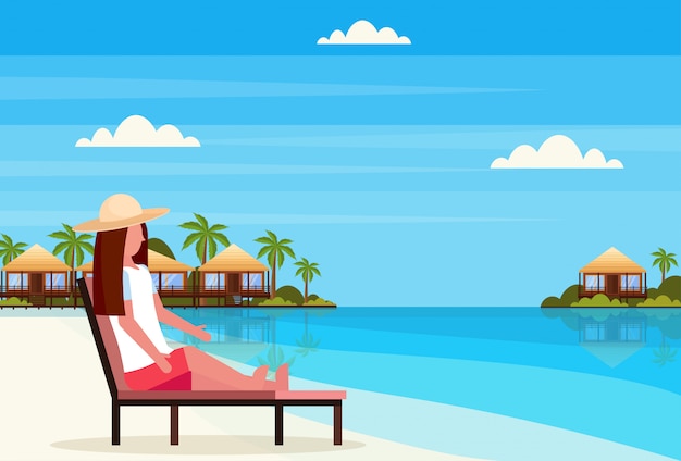 woman sitting sun bed lounge chair on tropical island villa bungalow hotel beach seaside green palms landscape summer vacation flat 