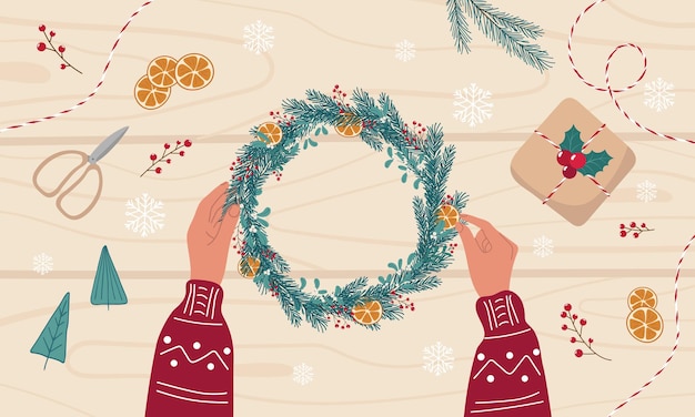 Womens hands make a christmas wreath from pine branches and organic decorations on wooden desk