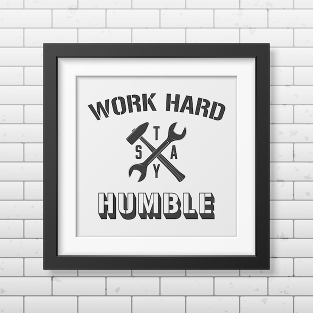 Work hard, stay humble - Quote typographical Background in realistic square black frame on the brick wall background .