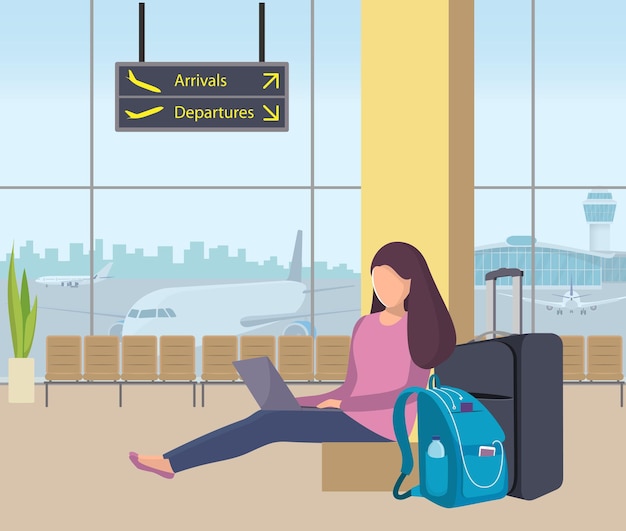 Young woman sitting in airport lounge with her suitcase and backpack and working on a laptop